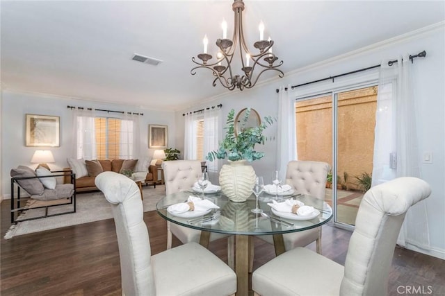 dining area featuring ornamental molding, visible vents, a notable chandelier, and wood finished floors