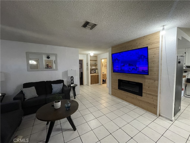 living area with wooden walls, visible vents, built in features, a textured ceiling, and a fireplace