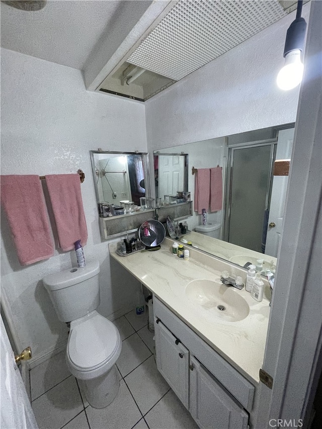 full bathroom featuring a textured wall, toilet, a stall shower, vanity, and tile patterned floors