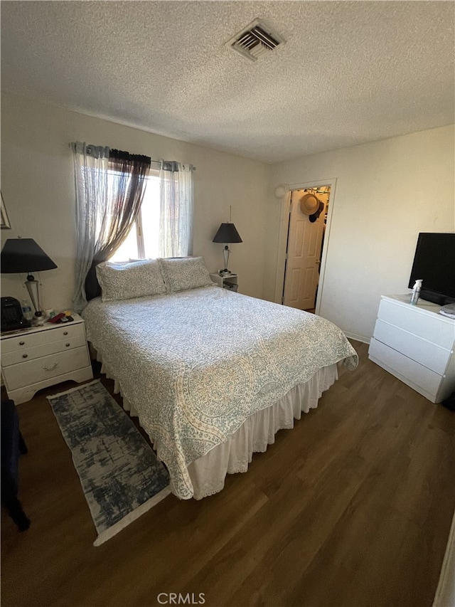 bedroom featuring a textured ceiling, dark wood-type flooring, and visible vents