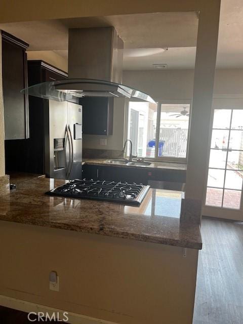 kitchen with stone countertops, a sink, wood finished floors, a ceiling fan, and island exhaust hood