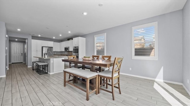 dining space with light wood-style floors, baseboards, and recessed lighting