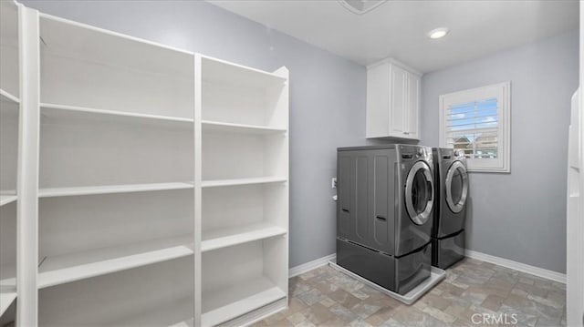 clothes washing area featuring stone finish floor, cabinet space, baseboards, and separate washer and dryer