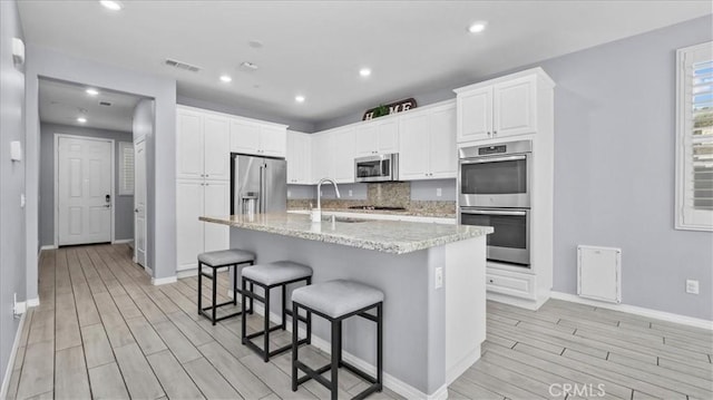 kitchen with a kitchen bar, visible vents, stainless steel appliances, and wood finish floors