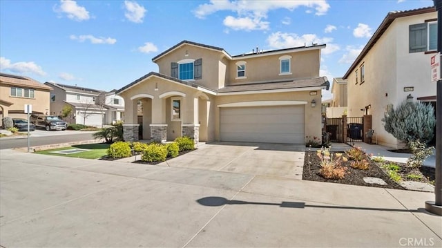 view of front of home with stucco siding, concrete driveway, an attached garage, a gate, and stone siding