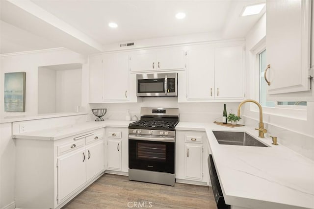 kitchen featuring a sink, visible vents, white cabinetry, appliances with stainless steel finishes, and light wood-type flooring