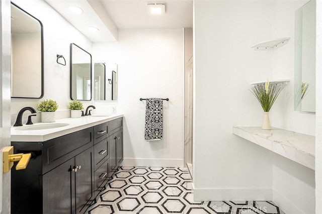 full bath featuring double vanity, baseboards, a sink, and tile patterned floors