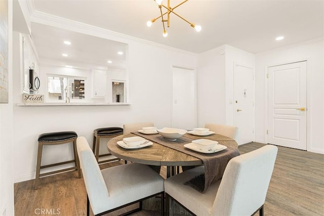 dining area featuring a notable chandelier, crown molding, wood finished floors, and recessed lighting