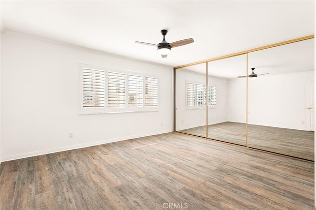 unfurnished bedroom with ceiling fan, a closet, baseboards, and wood finished floors