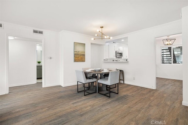 dining room with baseboards, visible vents, dark wood finished floors, an inviting chandelier, and crown molding