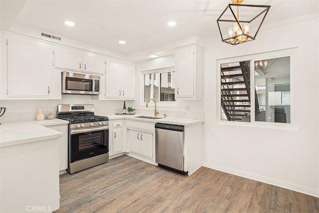 kitchen featuring stainless steel appliances, a sink, visible vents, white cabinets, and light wood finished floors