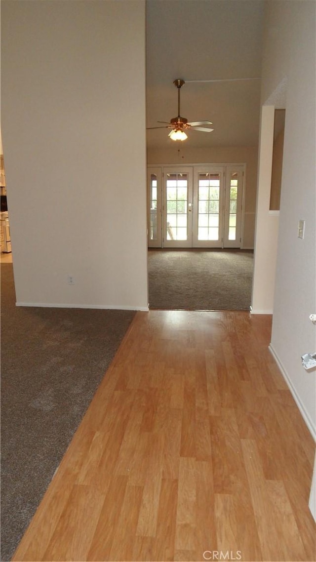 carpeted empty room featuring ceiling fan, baseboards, and wood finished floors