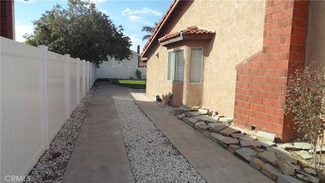 view of property exterior with a fenced backyard, a tiled roof, and stucco siding