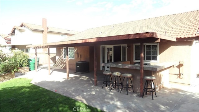 back of house with outdoor dry bar, a patio, a tiled roof, and stucco siding