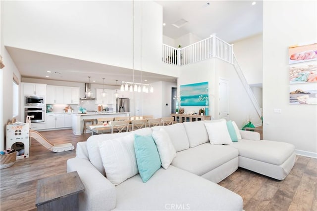 living room with recessed lighting, a high ceiling, and light wood finished floors