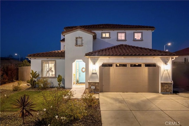 mediterranean / spanish-style home with an attached garage, driveway, a tile roof, and stucco siding