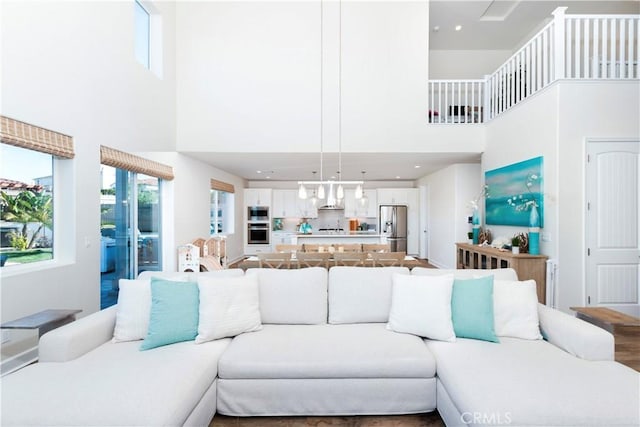 living room featuring recessed lighting, a towering ceiling, and wood finished floors