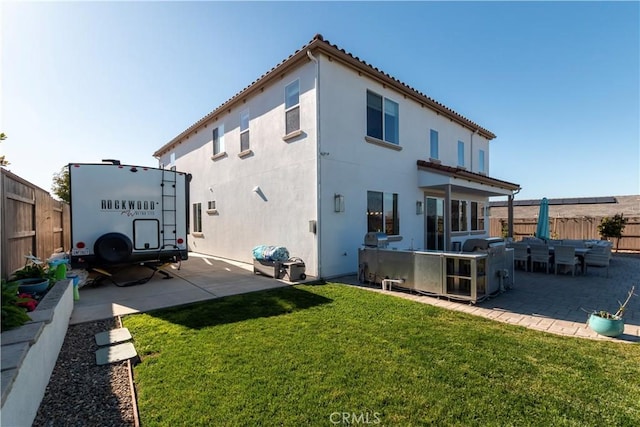 back of house featuring a lawn, a patio area, fence, and stucco siding