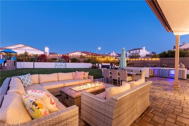 view of patio with outdoor dining space, an outdoor living space with a fire pit, fence, and a playground