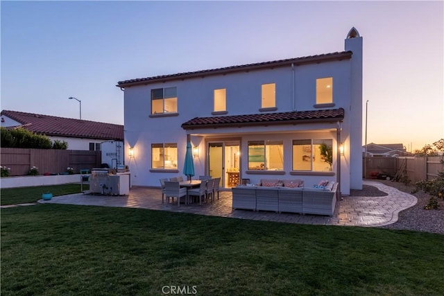 back of property at dusk featuring a patio area, a yard, outdoor lounge area, and a fenced backyard