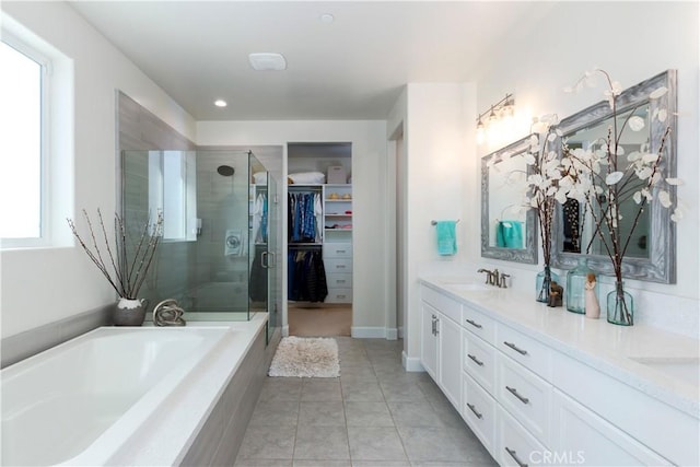 full bath with double vanity, a stall shower, a garden tub, a spacious closet, and a sink