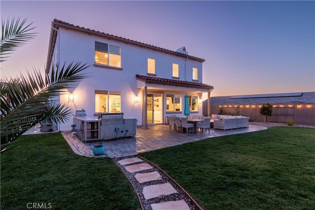 back of house at dusk featuring a patio, a yard, stucco siding, an outdoor hangout area, and fence