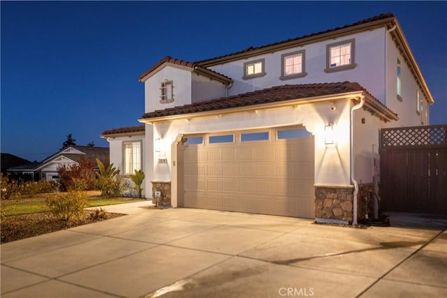 mediterranean / spanish-style house with driveway, a garage, fence, and stucco siding