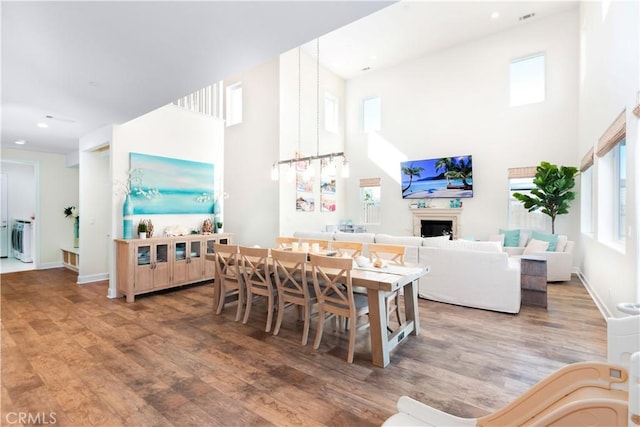 dining space with baseboards, a fireplace, a high ceiling, and wood finished floors