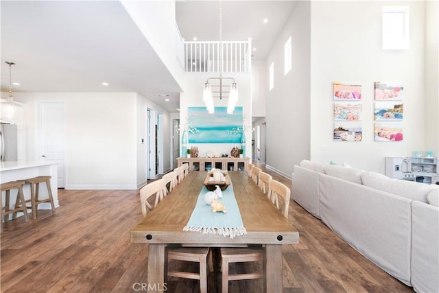 dining space featuring recessed lighting, wood finished floors, a towering ceiling, and baseboards