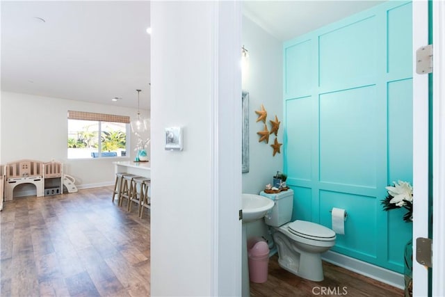 bathroom with wood finished floors, toilet, and a decorative wall