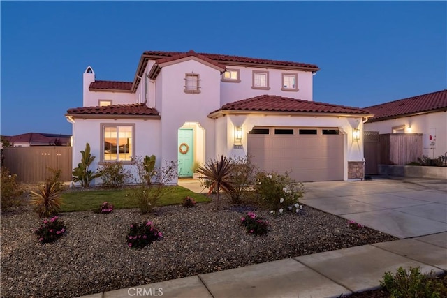 mediterranean / spanish home featuring a garage, fence, driveway, a tiled roof, and stucco siding