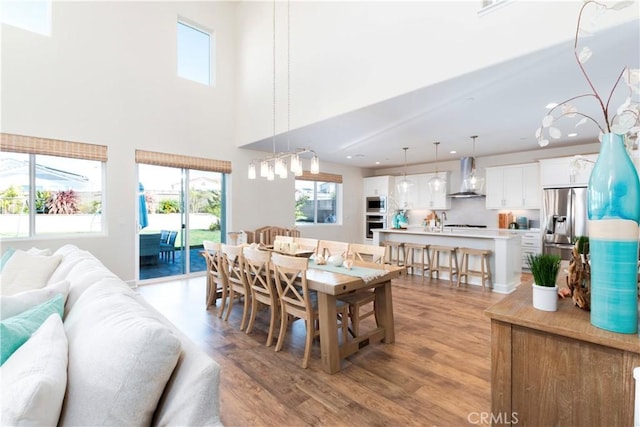 dining room featuring a high ceiling, recessed lighting, and light wood-style floors