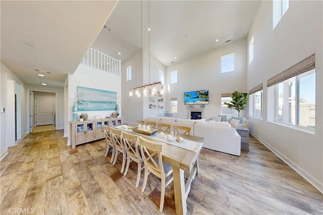 dining room with light wood-type flooring, a fireplace, visible vents, and baseboards