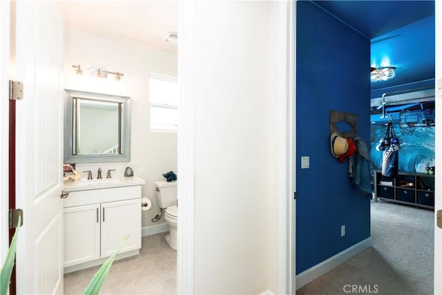 half bath featuring tile patterned flooring, baseboards, vanity, and toilet