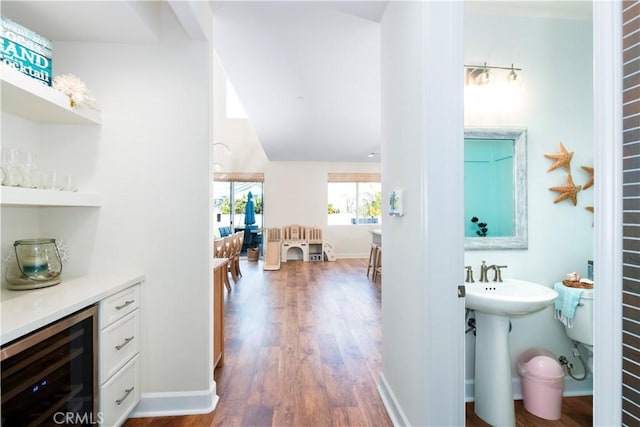 interior space with a dry bar, beverage cooler, baseboards, and wood finished floors