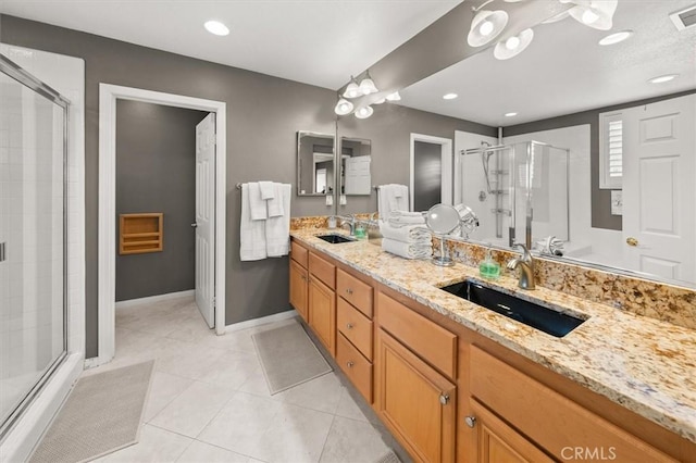 bathroom with double vanity, a stall shower, a sink, and tile patterned floors