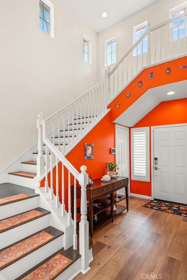 foyer featuring a high ceiling, stairway, wood finished floors, and recessed lighting