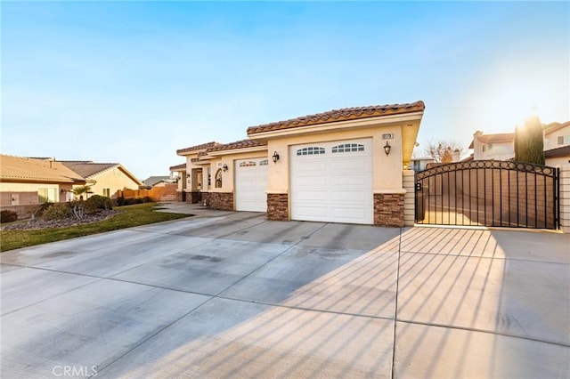 view of front of house featuring a garage, concrete driveway, stone siding, a gate, and stucco siding