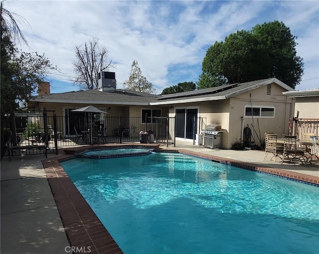 view of pool with a pool with connected hot tub, a patio area, a grill, and fence