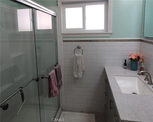 full bathroom with a stall shower, wainscoting, tile walls, and vanity