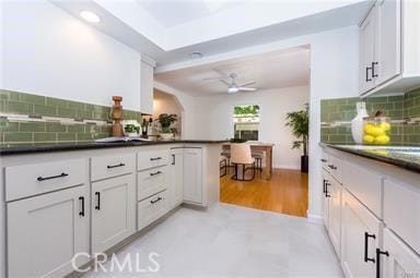 kitchen with a ceiling fan, dark countertops, white cabinets, and decorative backsplash