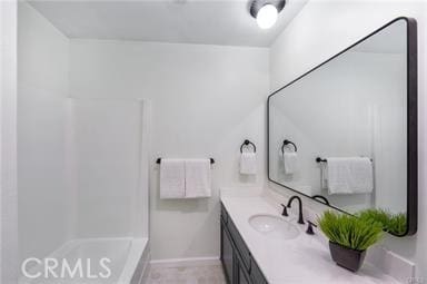 bathroom with walk in shower, vanity, and baseboards