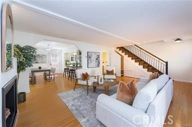 living room featuring stairs, a fireplace, and wood finished floors