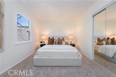 carpeted bedroom featuring a closet and baseboards