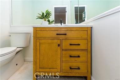 bathroom featuring toilet, baseboards, and vanity