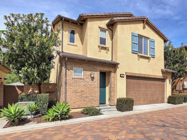 view of front of home featuring a garage, decorative driveway, fence, and stucco siding