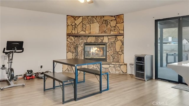 office space featuring a stone fireplace, wine cooler, and wood finished floors