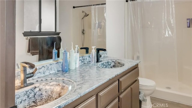 bathroom featuring double vanity, a sink, toilet, and a shower stall