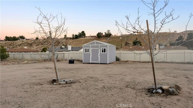 view of yard with a fenced backyard, a shed, and an outbuilding