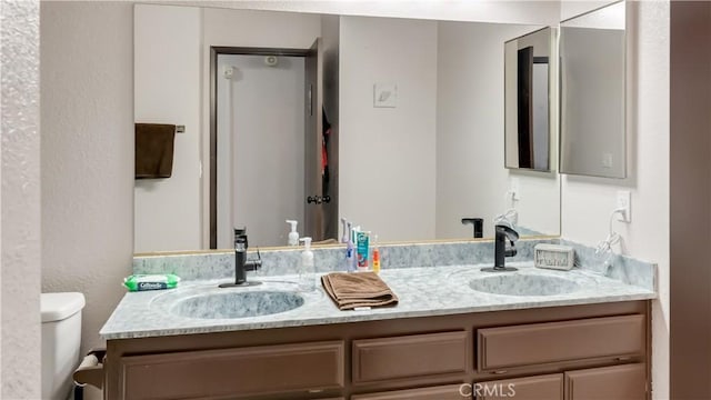 bathroom featuring double vanity, a sink, and toilet